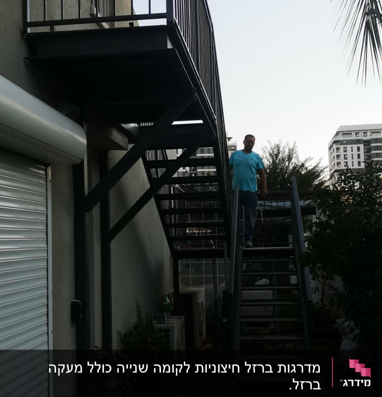 אדם עומד על מדרגות מתכת חיצוניות ליד מבנה